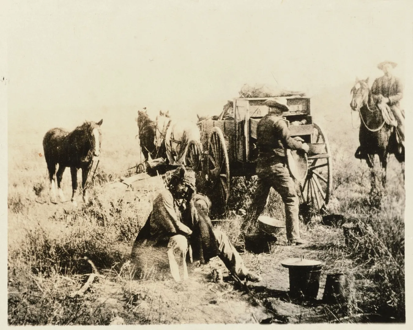 Cowboys working around the Maltese Cross chuck wagon