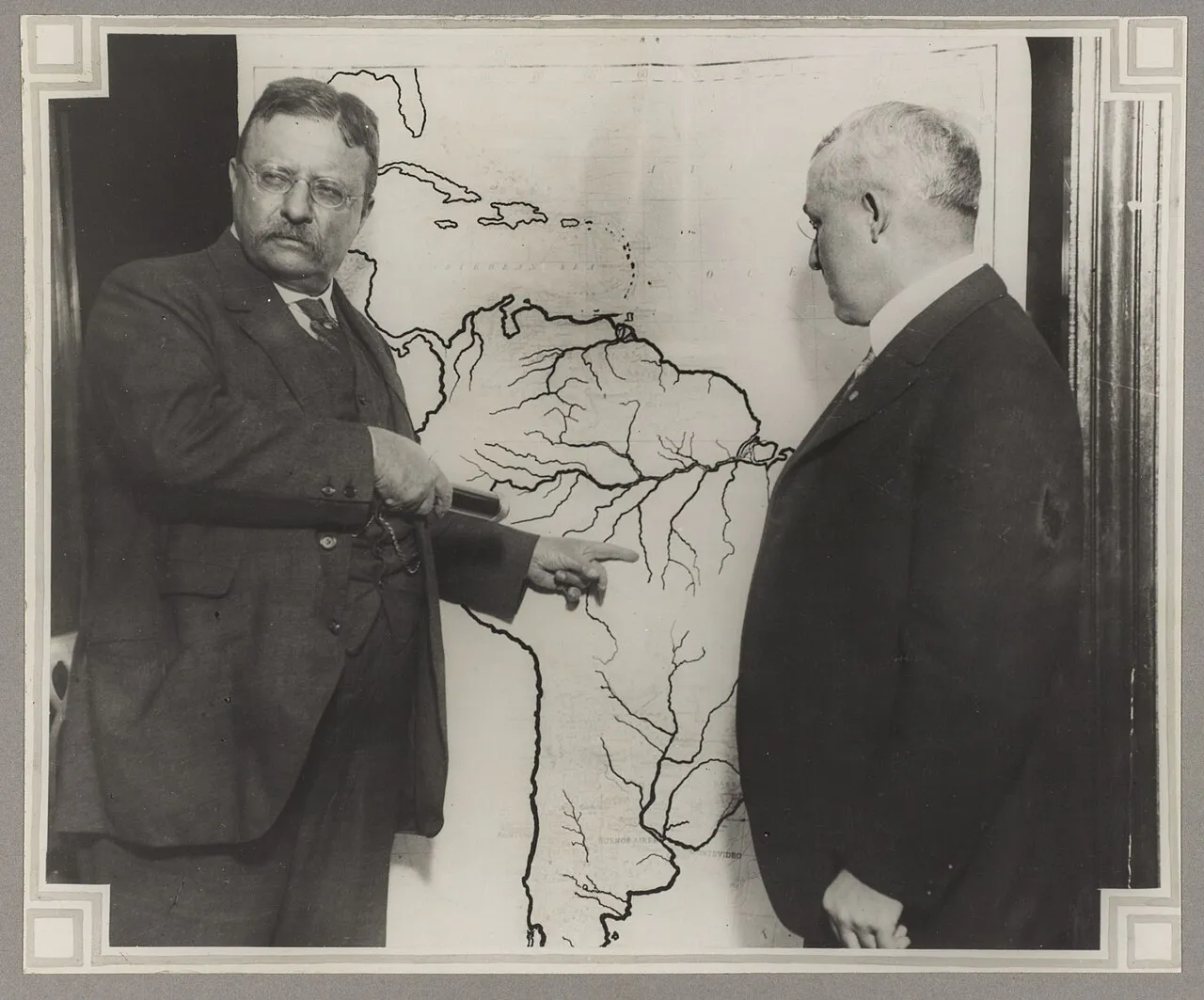 Theodore Roosevelt pointing to a map of the area explored in Brazil