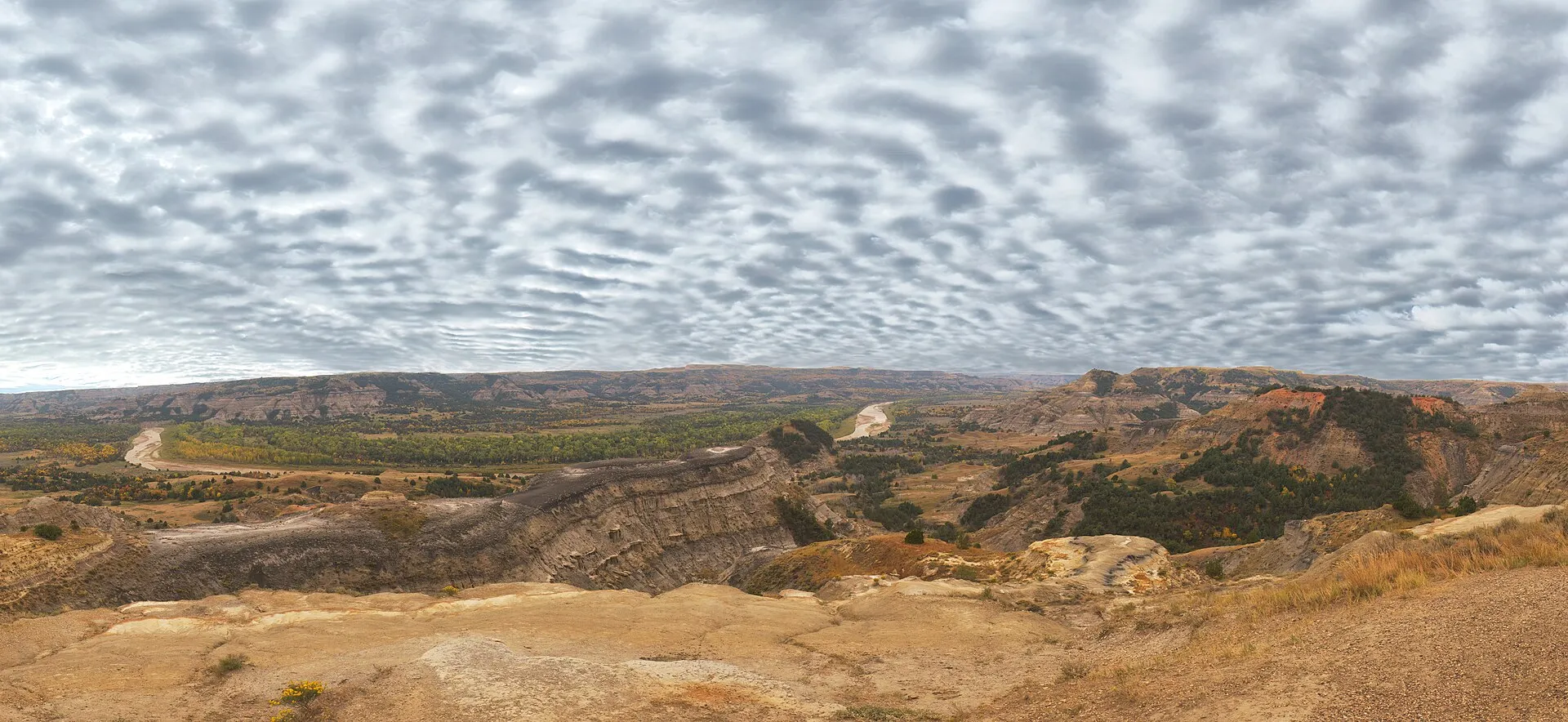 Sweeping overlook of layered Badlands buttes, prairie, and river valley in Theodore Roosevelt National Park