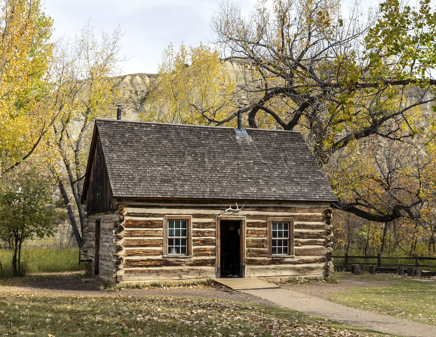 The restored log Maltese Cross Cabin among cottonwood trees at Theodore Roosevelt National Park