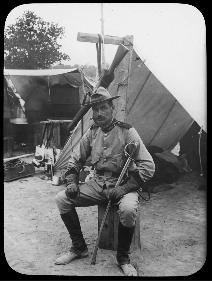 Rough Rider Captain Woodbury Kane seated by his tent