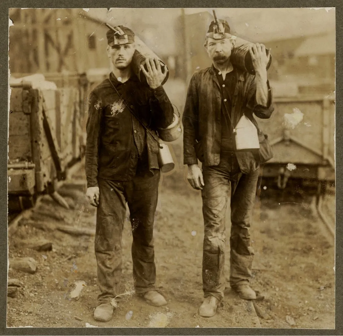 Two anthracite coal miners at the end of a shift, lamps on their caps