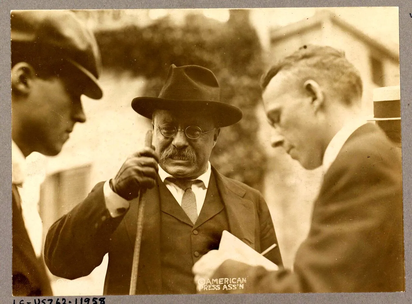 Theodore Roosevelt speaking with newsmen, papers in hand