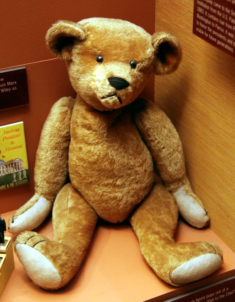 An early jointed mohair teddy bear from the early 1900s displayed in a museum case