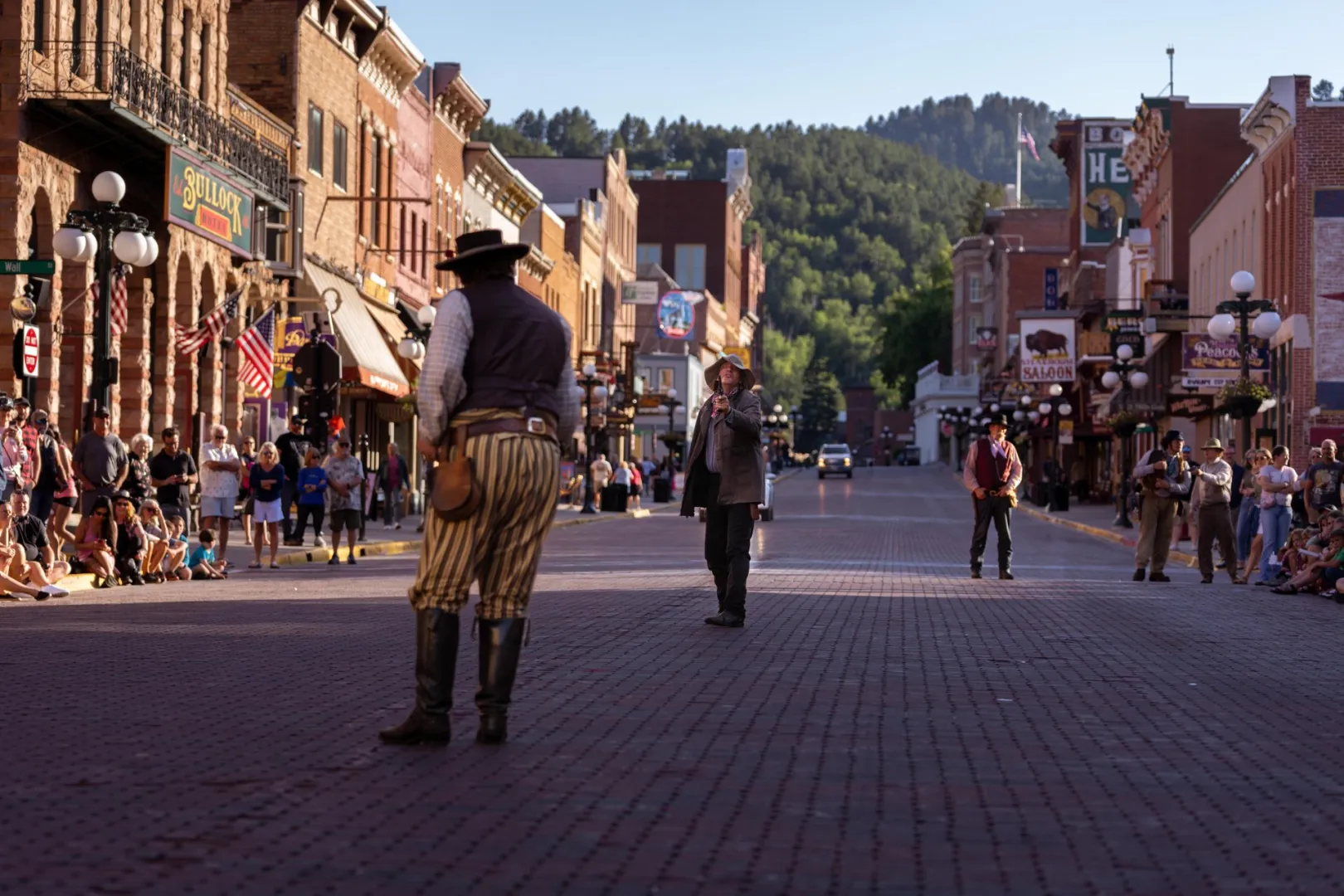 Re-enactors on the brick main street of historic Deadwood, South Dakota, with the Bullock Hotel sign above the crowd