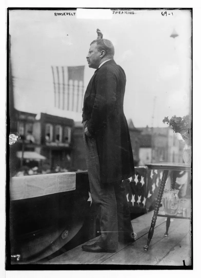 Theodore Roosevelt standing on a bunting-draped platform delivering a speech