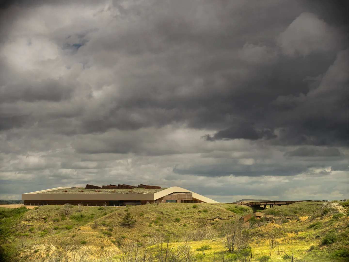 The Theodore Roosevelt Presidential Library on the butte above Medora, with the badlands below and storm clouds overhead