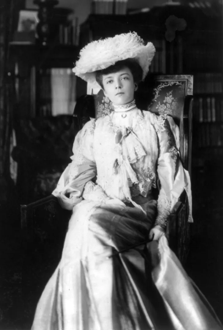 Portrait of a young Alice Roosevelt seated in a white gown with a large plumed hat