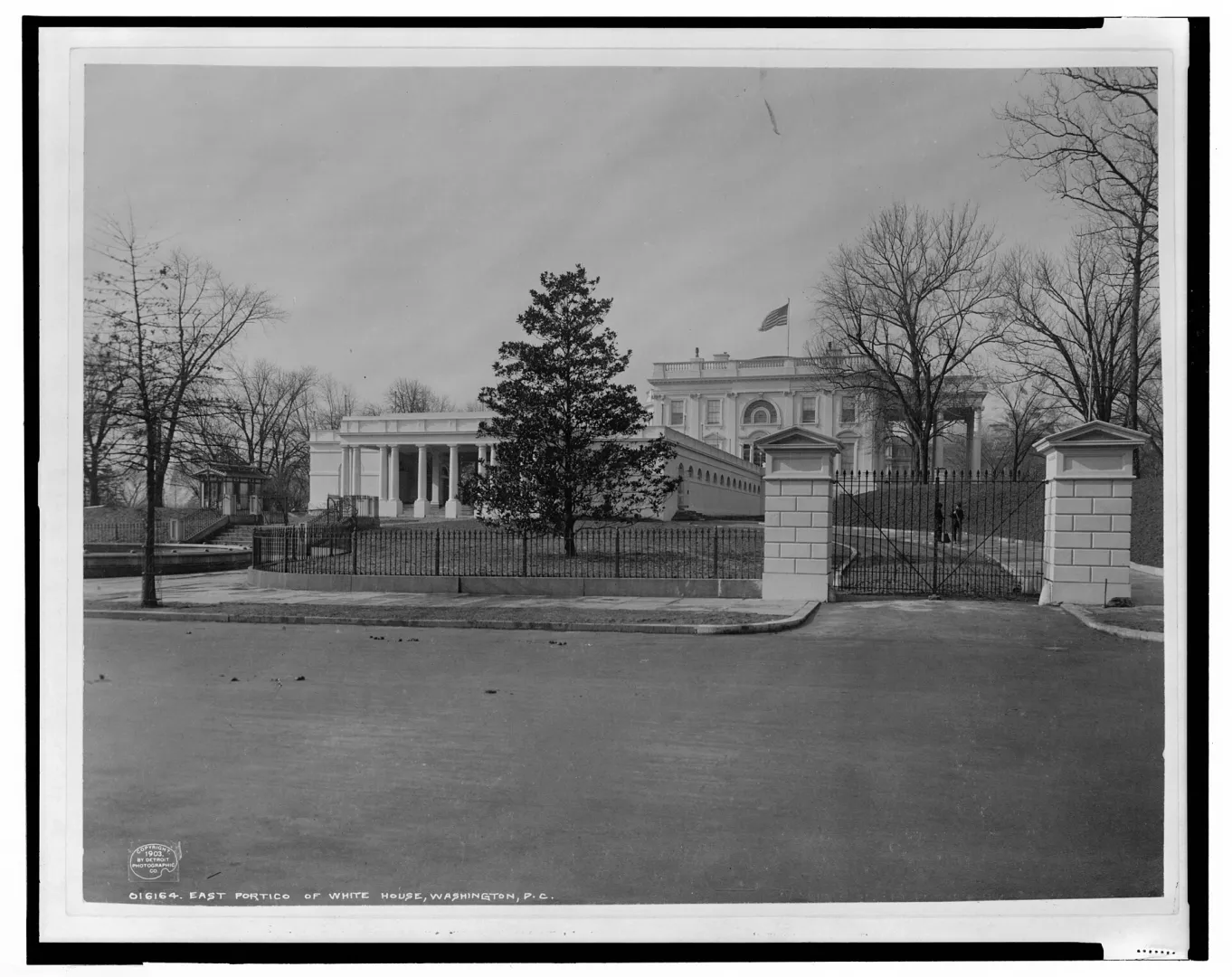 Photograph of the East Portico of the White House with its iron fence and gate, early twentieth century