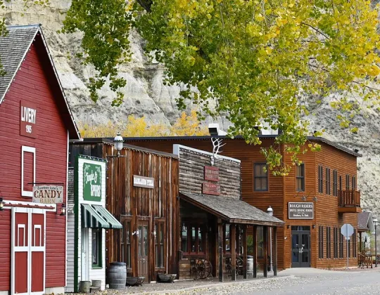 Historic storefronts on Main Street in Medora, North Dakota, under fall cottonwoods and Badlands bluffs.