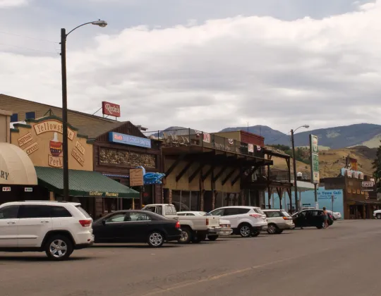 Storefronts along the main street of Gardiner, Montana, below dry hills