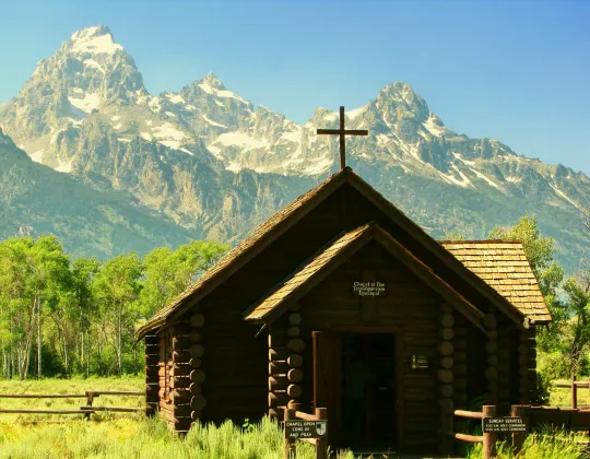 The small log Chapel of the Transfiguration with the Teton Range behind