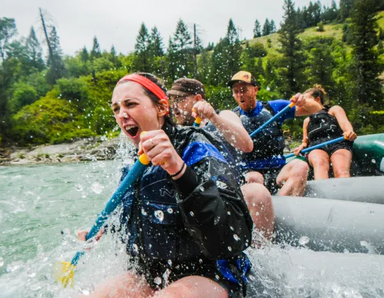 A raft of people splashing through rapids on the Snake River