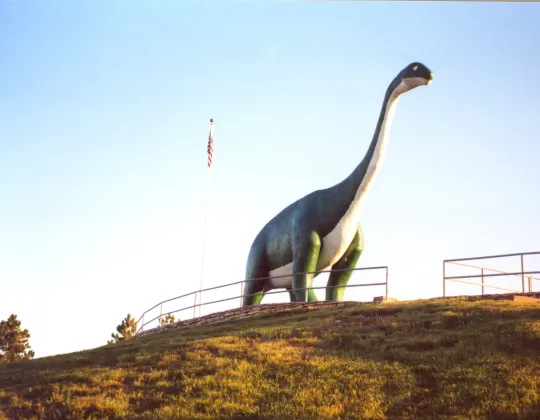 A green concrete dinosaur sculpture on a hilltop at Dinosaur Park in Rapid City