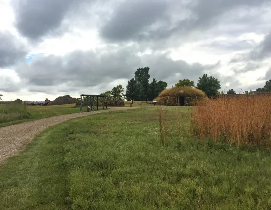 A trail through tall grass toward an earthlodge at Knife River