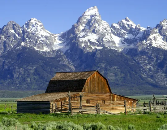 A weathered wooden barn below the Teton Range