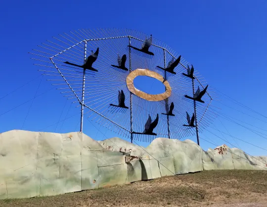 A flock of giant metal geese sculptures on a hilltop