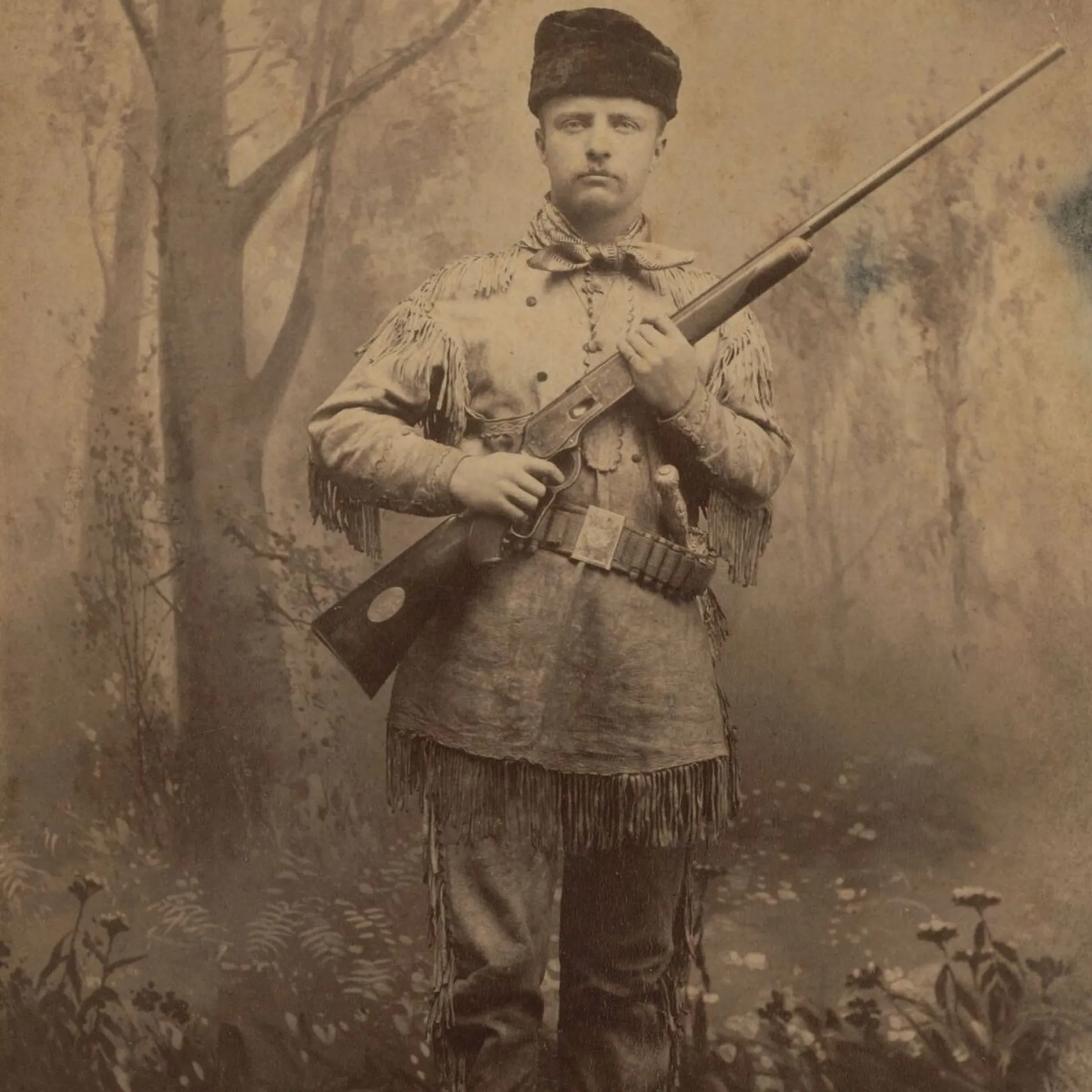 Theodore Roosevelt in buckskin standing guard with his rifle