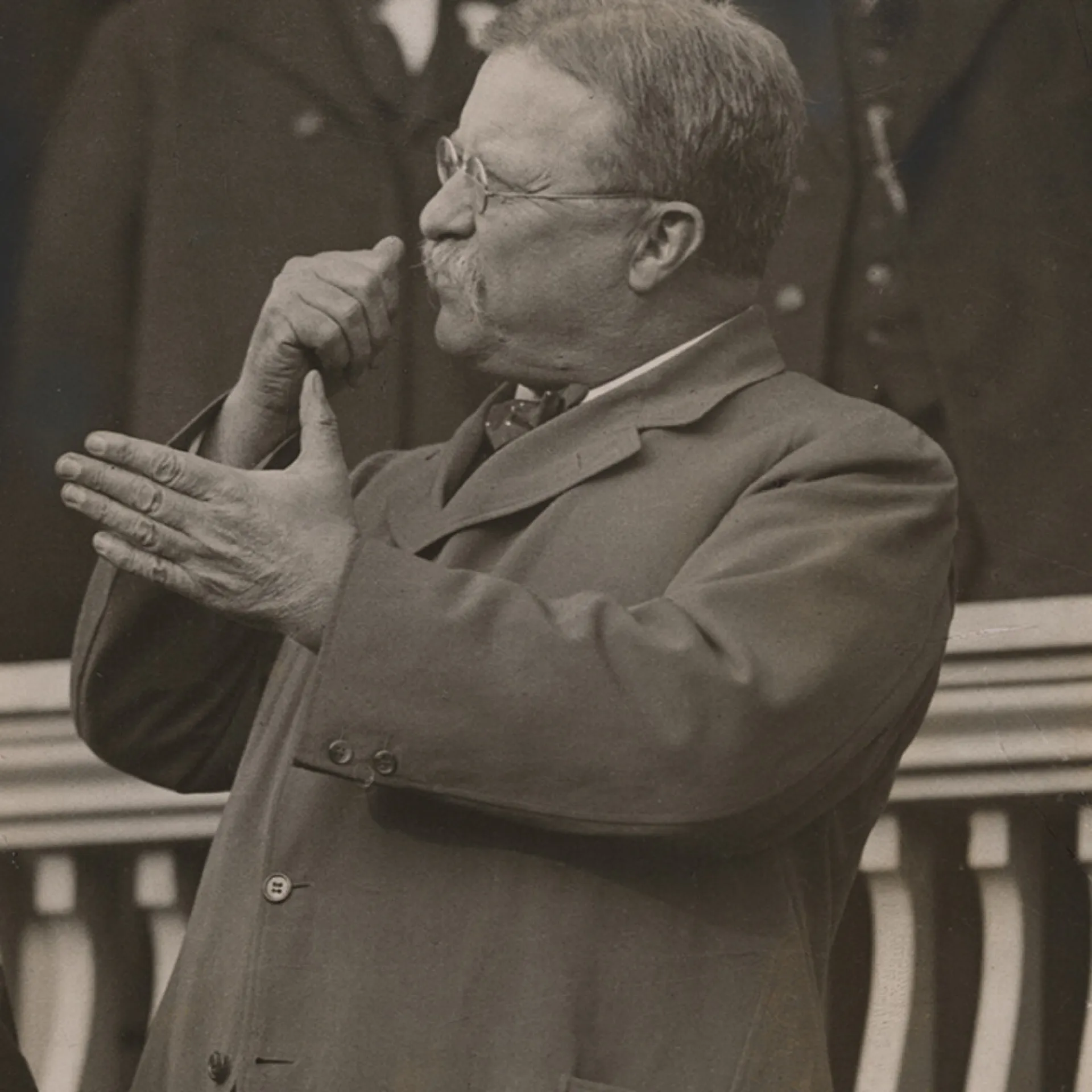 Theodore Roosevelt gesturing forcefully while delivering a speech from a balcony