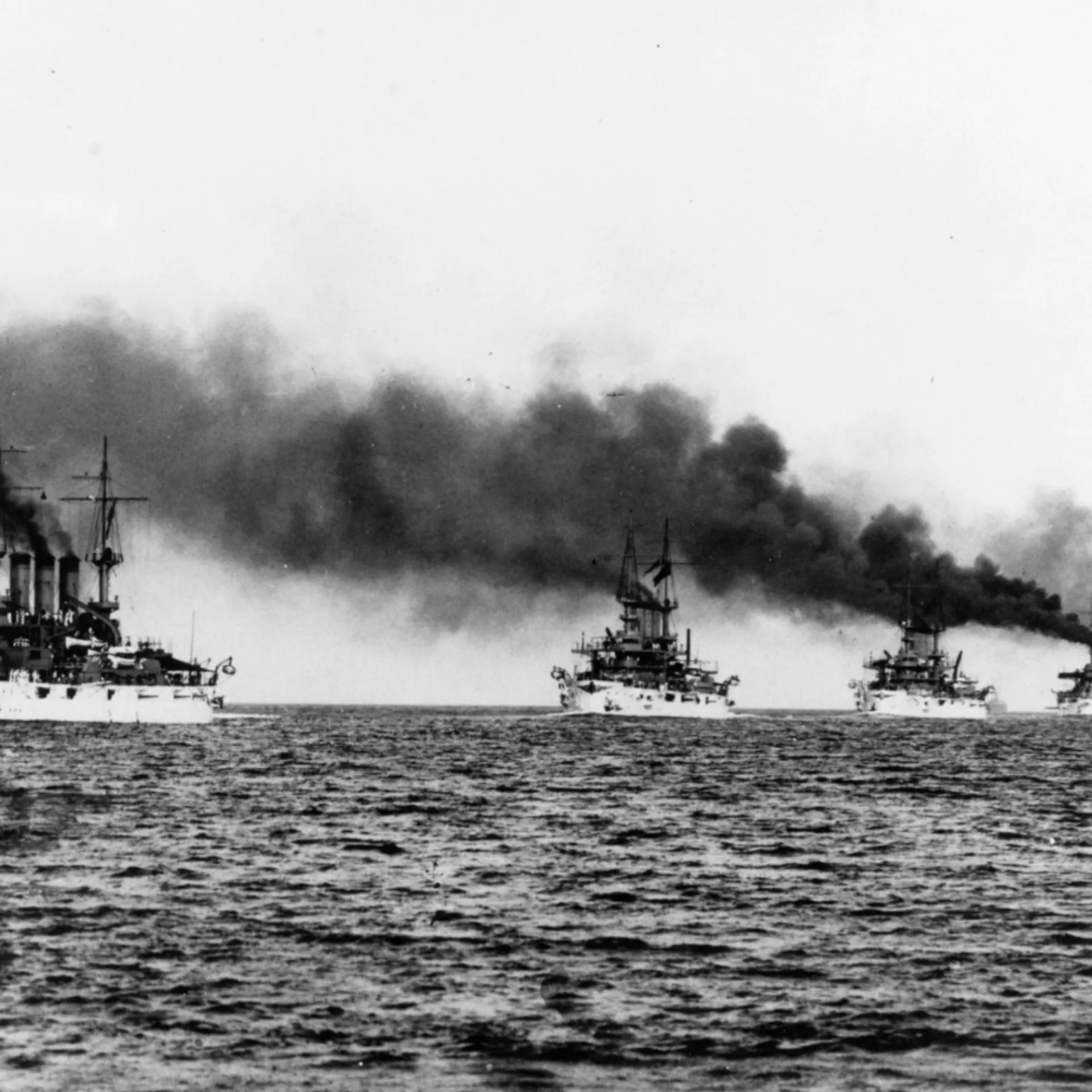 White-hulled battleships of the Atlantic Fleet steaming in column, coal smoke trailing from their stacks